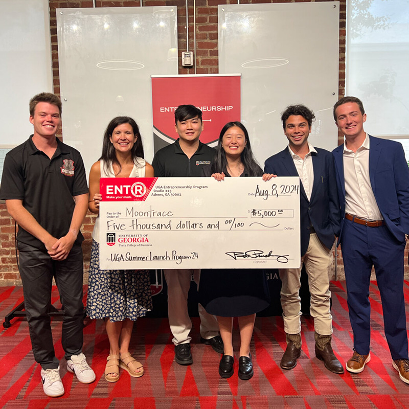 Participants in the 2024 Summer Launch pose with the founders of Mootrace and their giant  prize check.