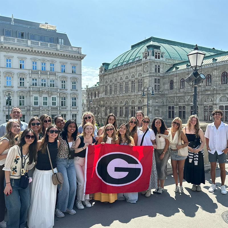 A group of Terry students poses with a UGA flag in front of the Vienna Opera House