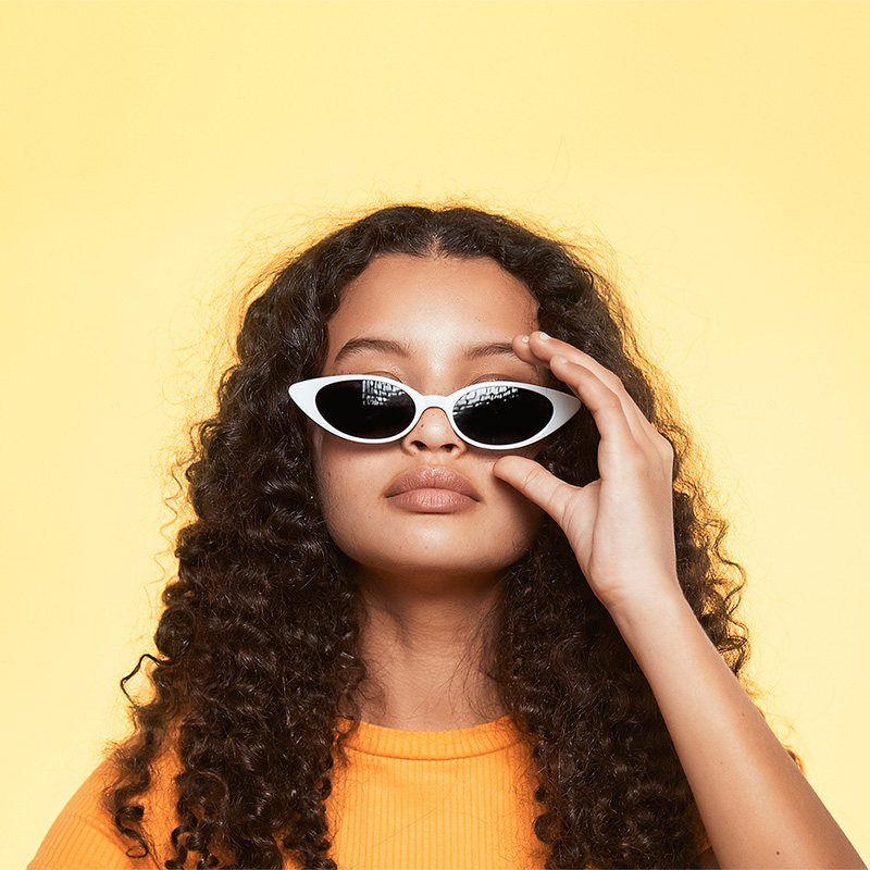 A young woman adjusting her very cool cat eye sunglasses