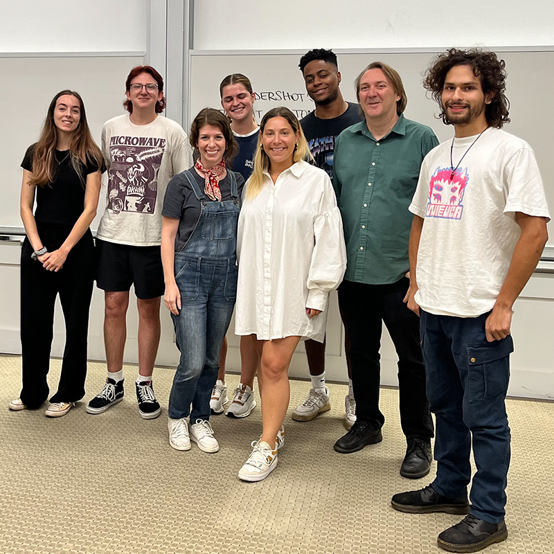 Julie Greenberg, center in white dress, stands with UGA Music Business Associate Director Lane Marie O'Kelley, Instructor Andrew Rieger and music business students in at Terry College classroom.