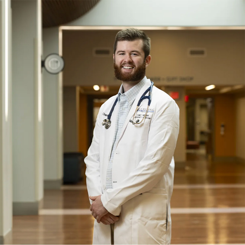 Chip Chambers poses in the hallway of a hospital in a doctor's white coat