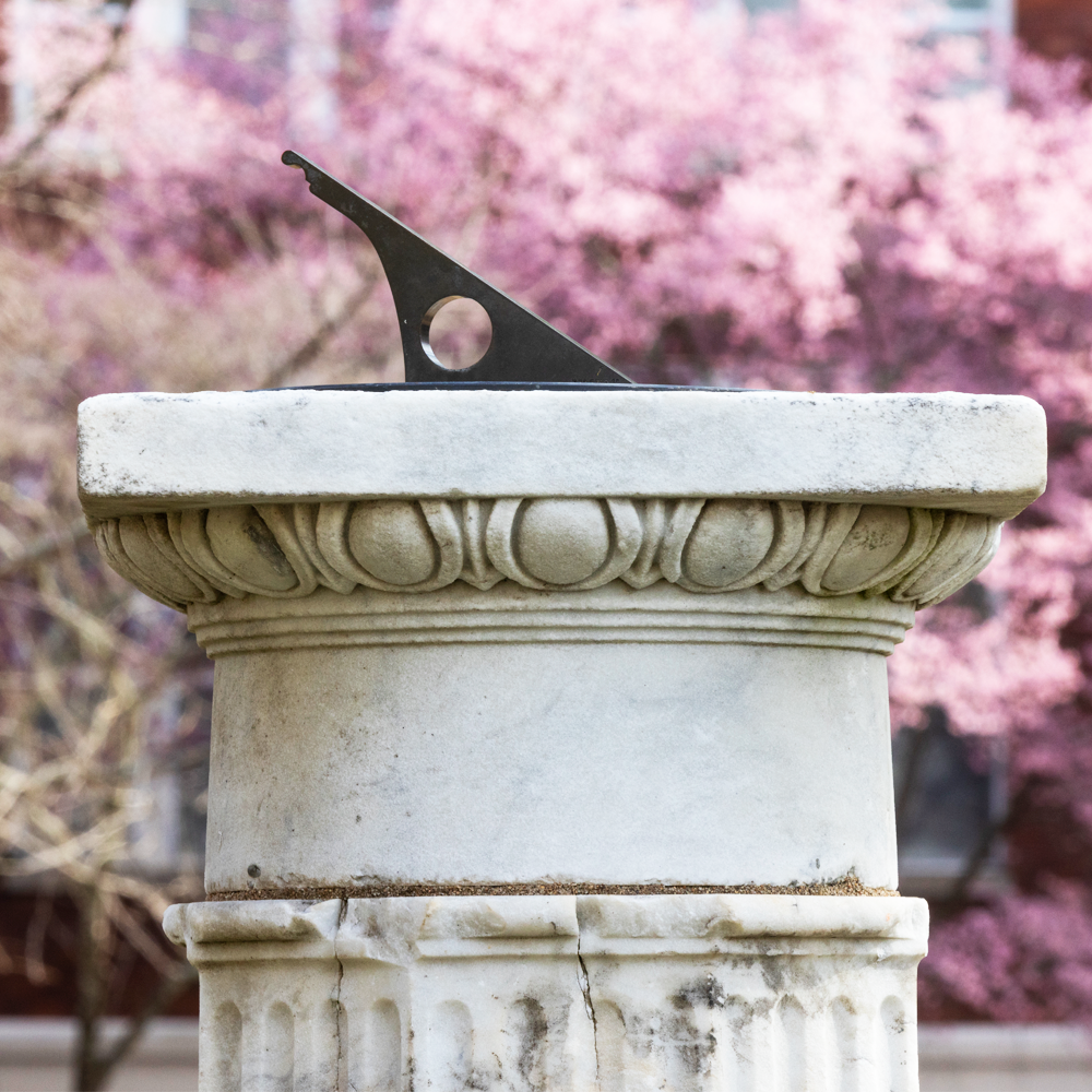 A sundial with redbud tree blooming in background (UGA MarComms)