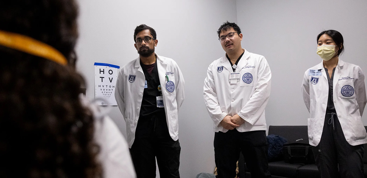 From left to right, AU/UGA Medical Partnership students Ganesh Prabakaran, David Tran and Serena Song watch as students receive vision screenings at the Clarke Middle Health Center. (Photo by Billy Schuerman/UGA)