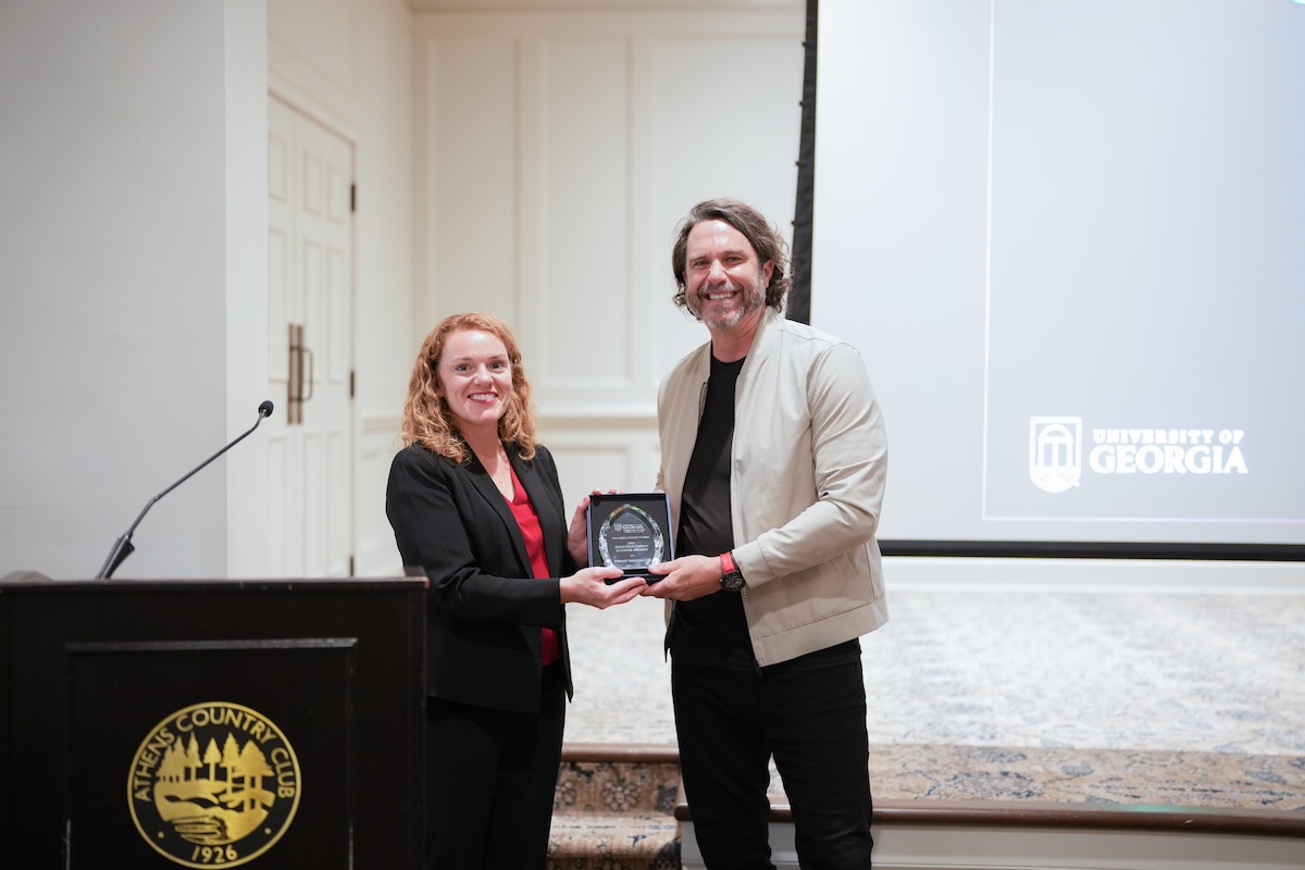 Margaret Christ and Tommy Breedlove hold an award and pose for photo