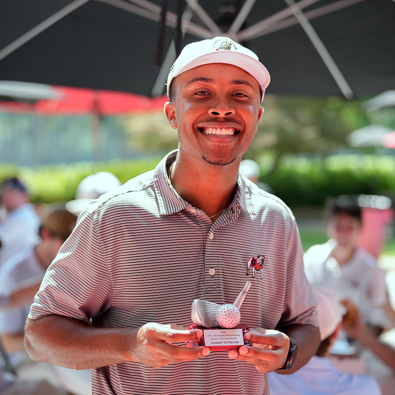 A student golfer poses with a trophy