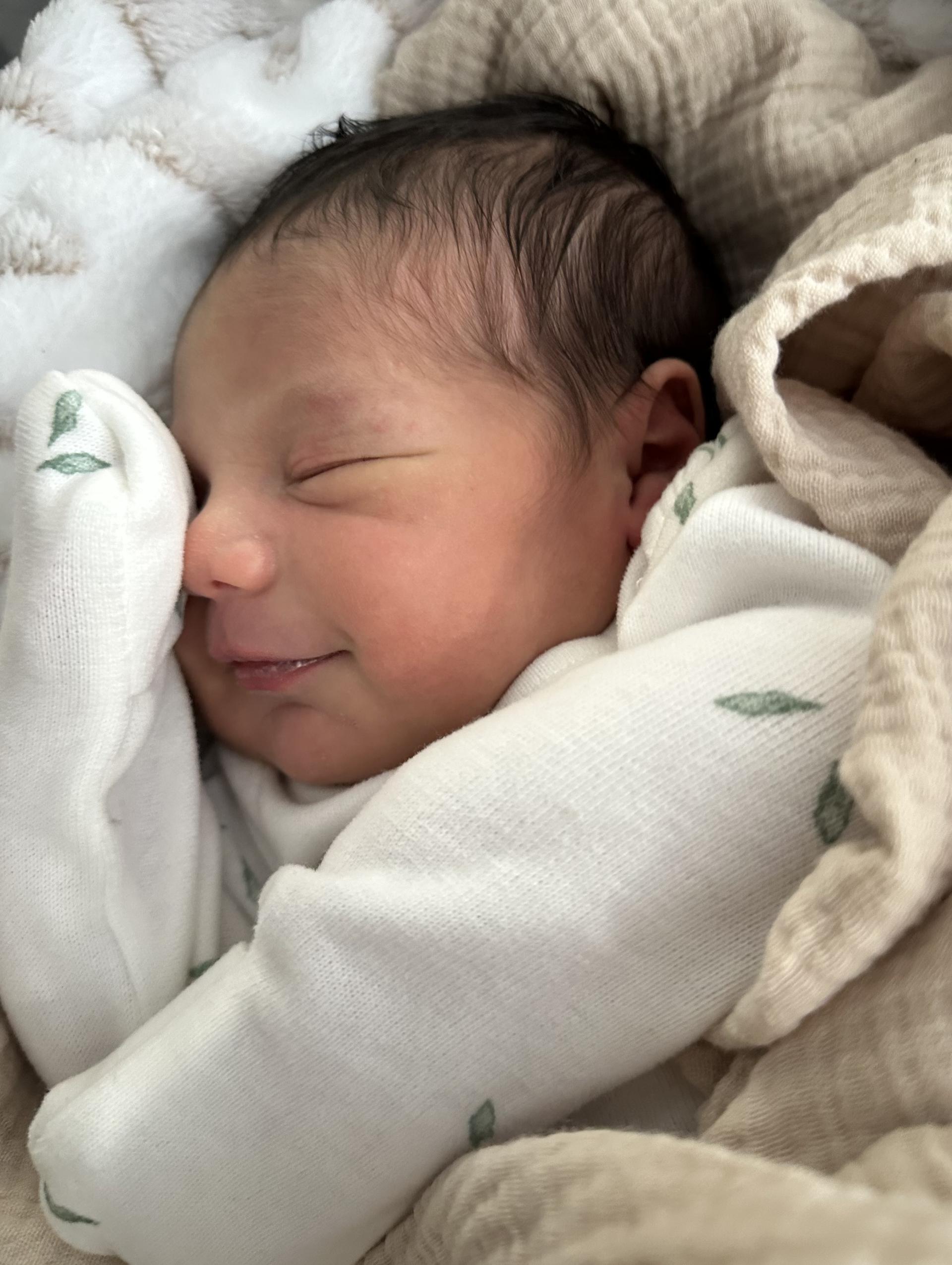 A happy newborn baby boy wrapped in blankets