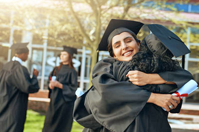 High-school graduate hugging friend holding a diploma