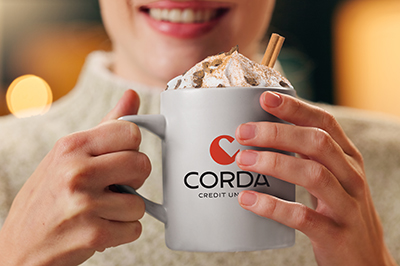 Smiling woman holding a Corda Credit Union mug with hot cocoa