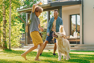 Family playing with dog on front lawn