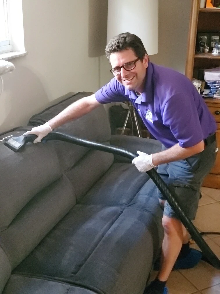 Upholstery cleaning technician using professional equipment to deep clean a microfiber couch — delivering fast, fabric-safe results Upholstery cleaning technician using professional equipment to deep clean a microfiber couch — delivering fast, fabric-safe results