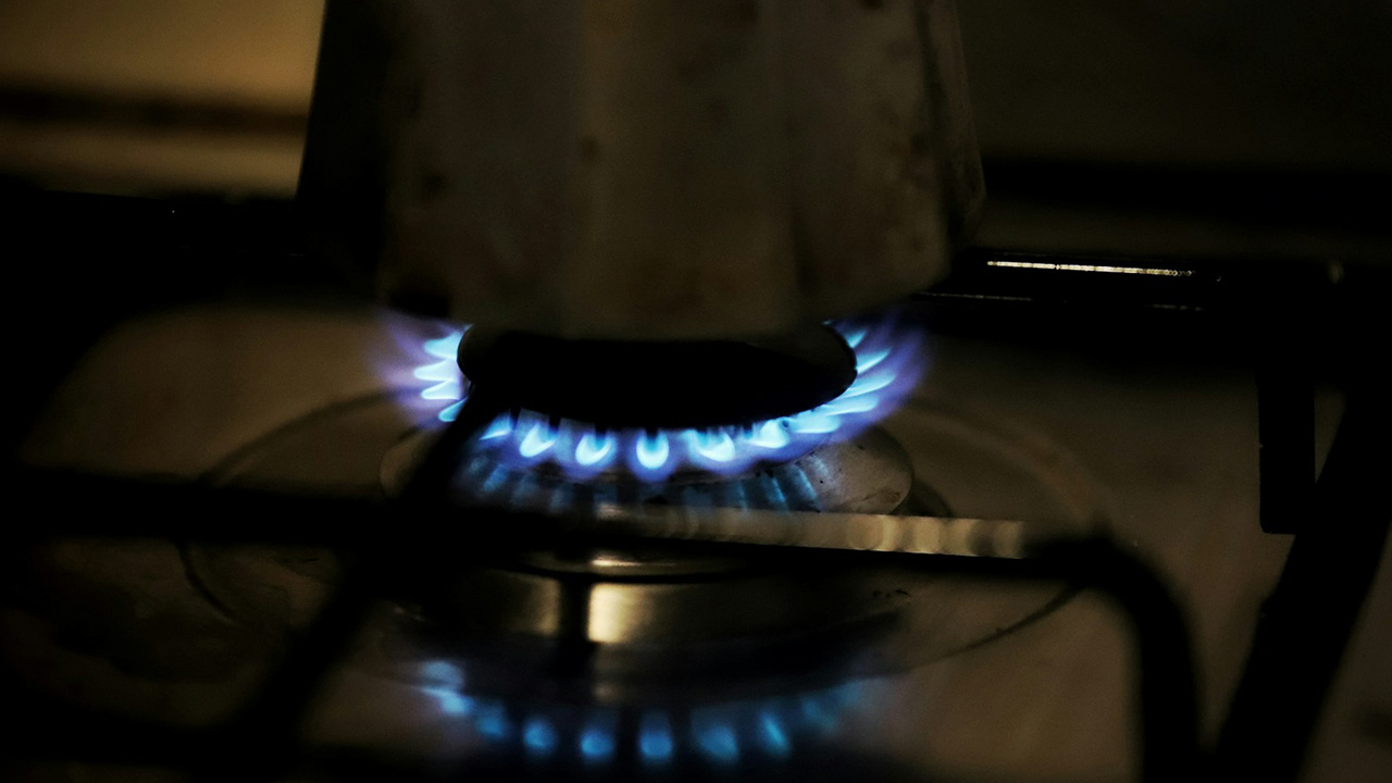 Blue gas flamed from a gas stove heating up a coffee maker.