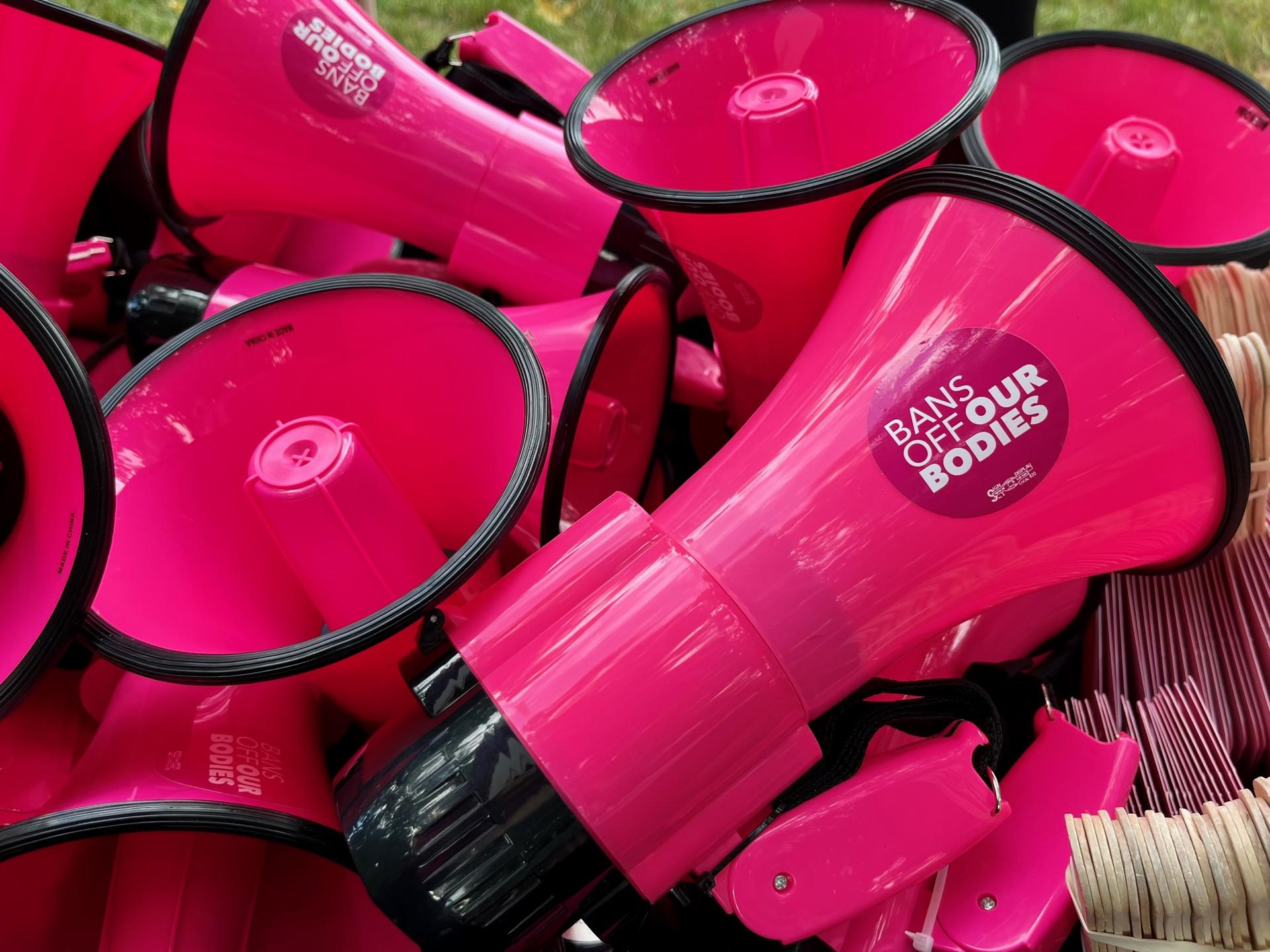 A stack of pink megaphones displaying circular ''Bans off our bodies'' stickers