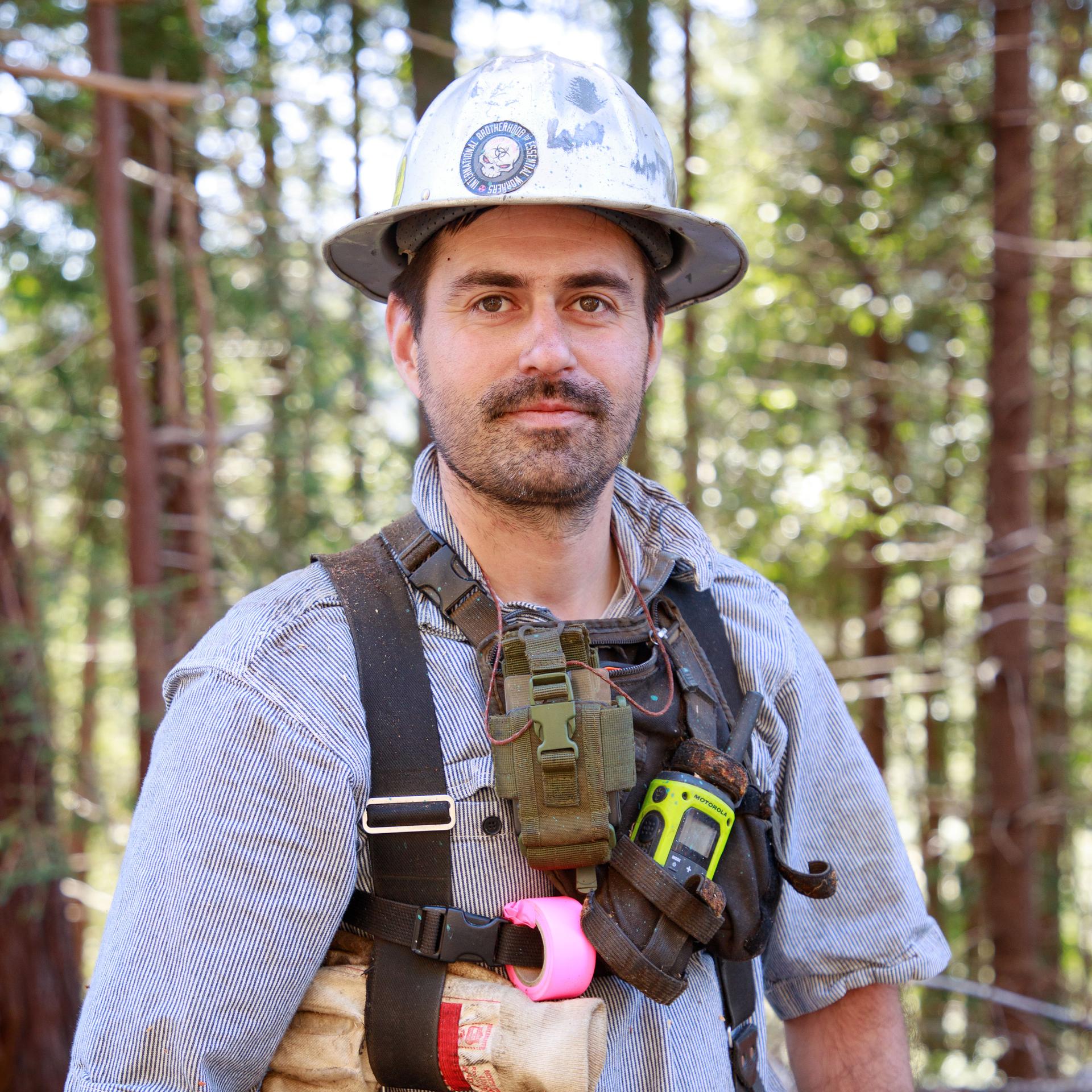 worker wearing a silver hard hard  and a harness with tools attached