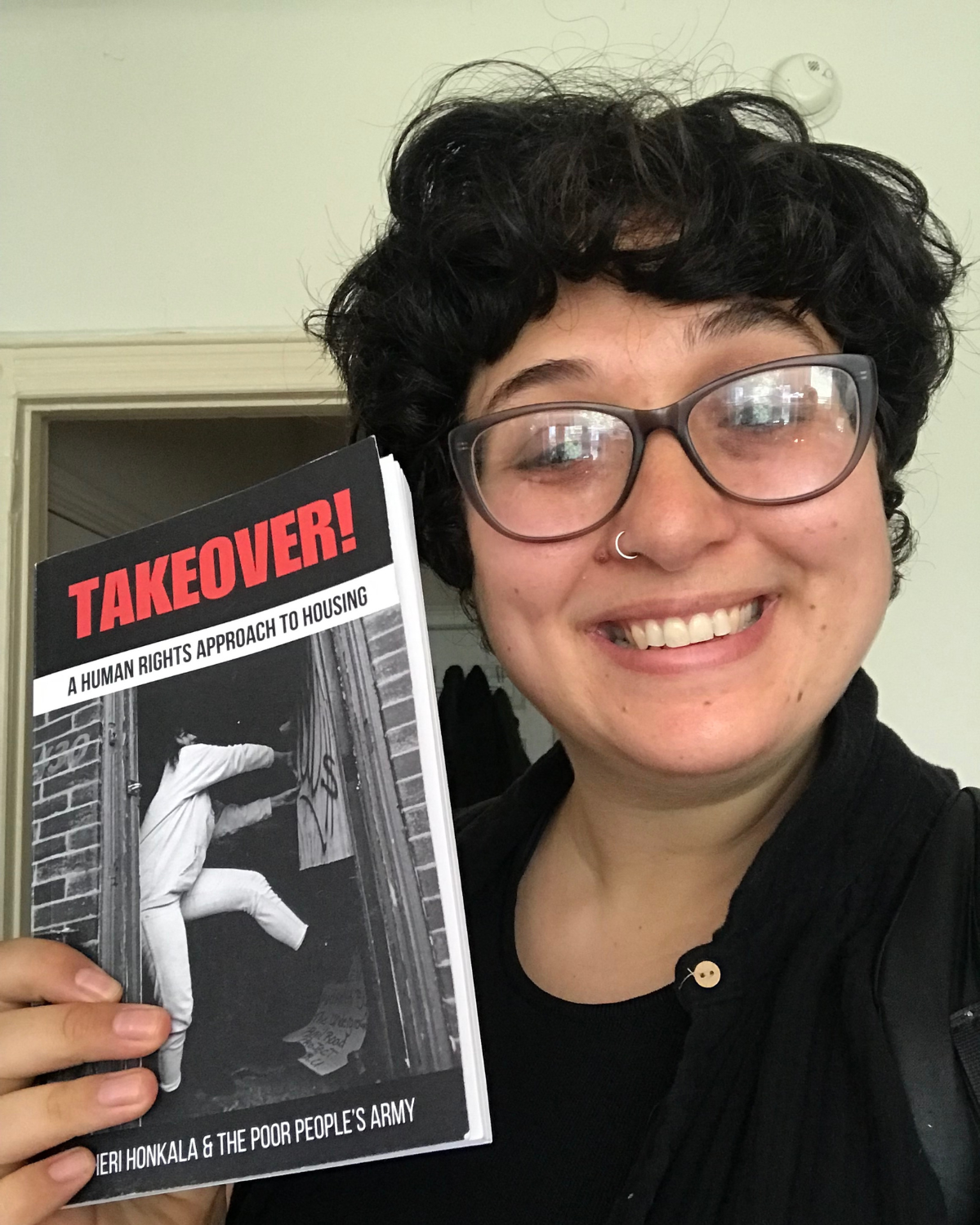 RG Philly member and contributing author/editor Alison posing with the book, showing you how happy & resolved that a better world is possible you'll be once you have it in your hands. 