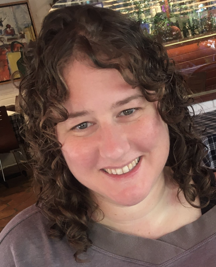 Tammy, a white woman with shoulder-length curly hair smiling at the camera