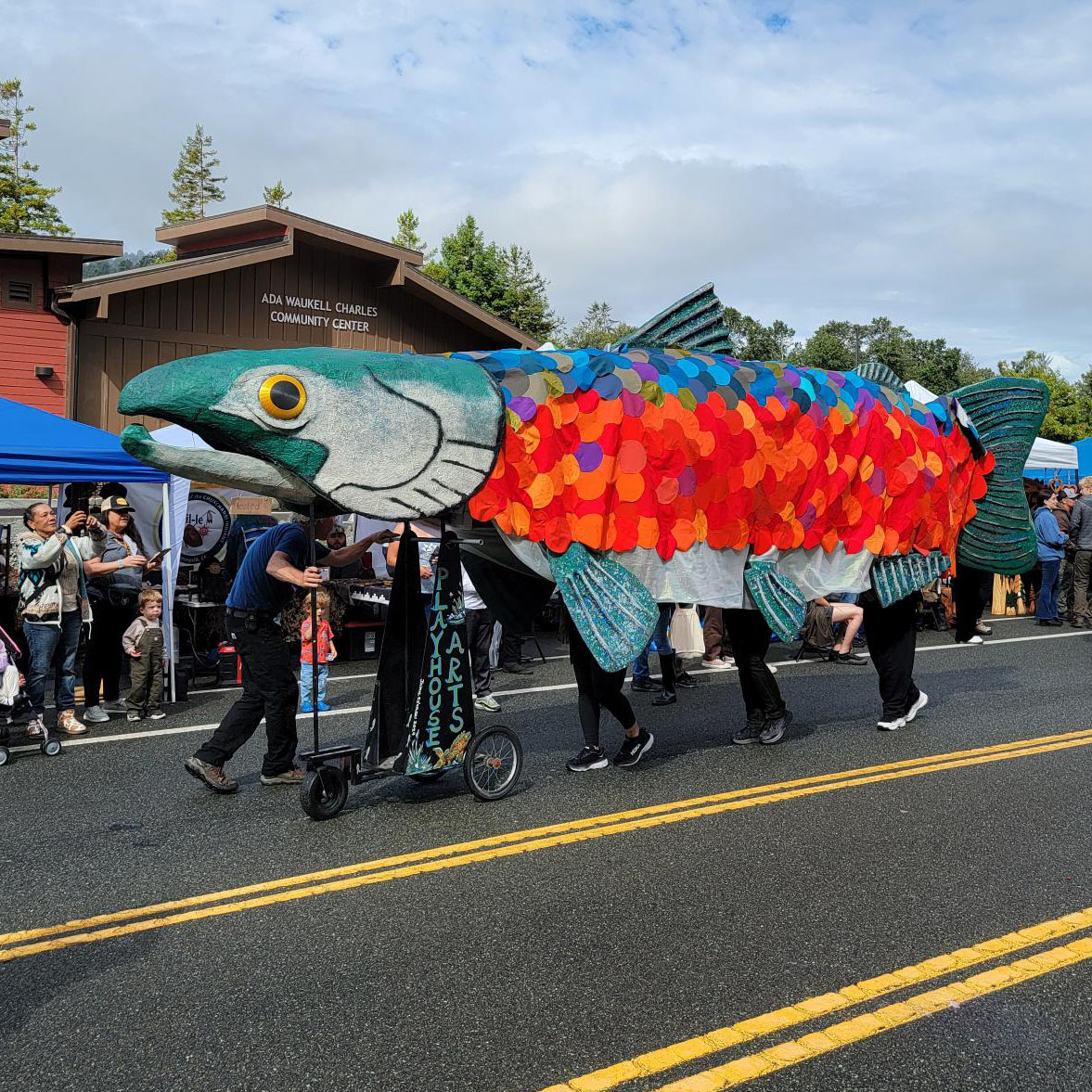 A street parade scene showing a huge, people-powered salmon
