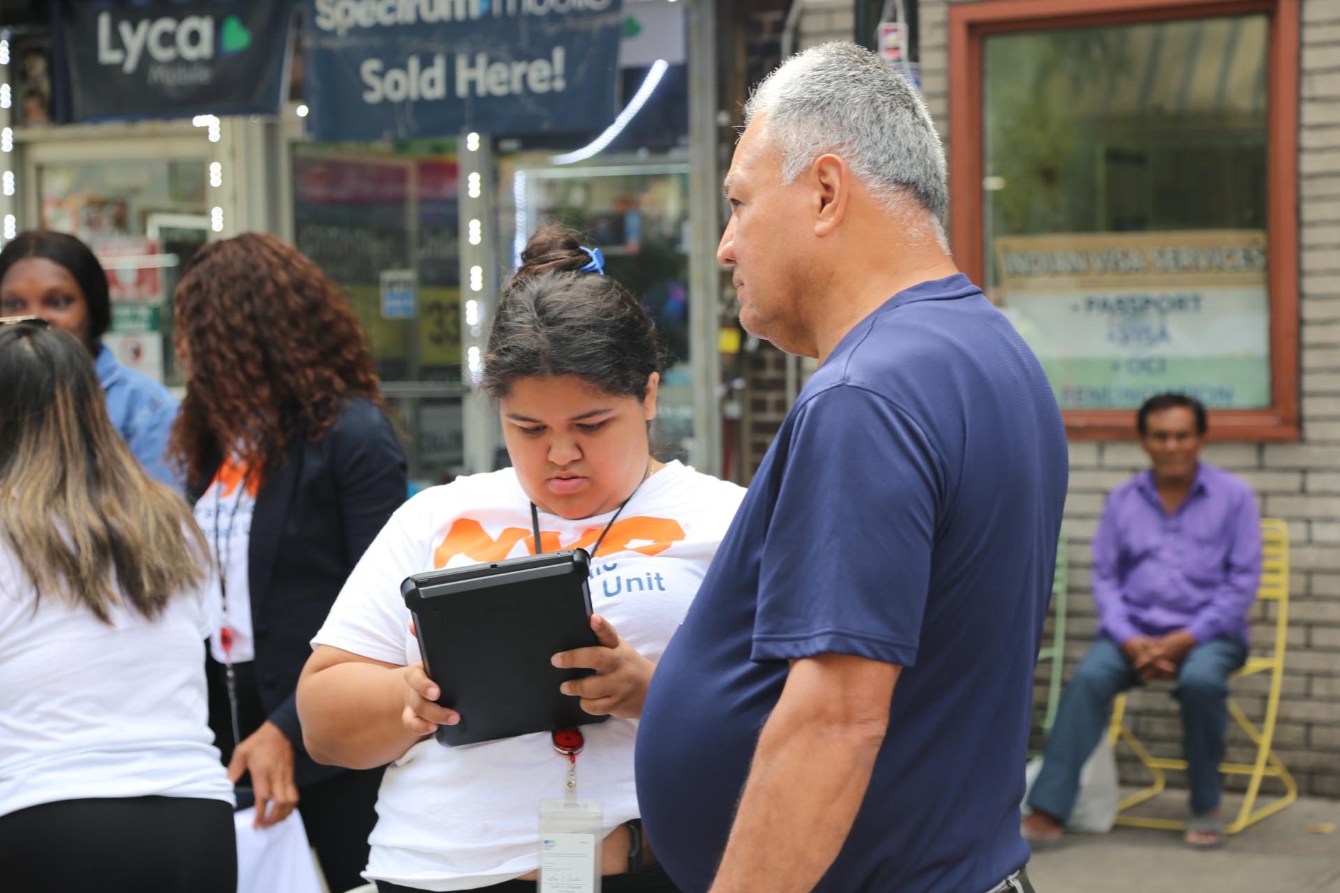 Picture of a PEU scanning a passerby for benefits. 