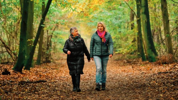 Twee vrouwen wandelen door een herfstig Kuinderbos