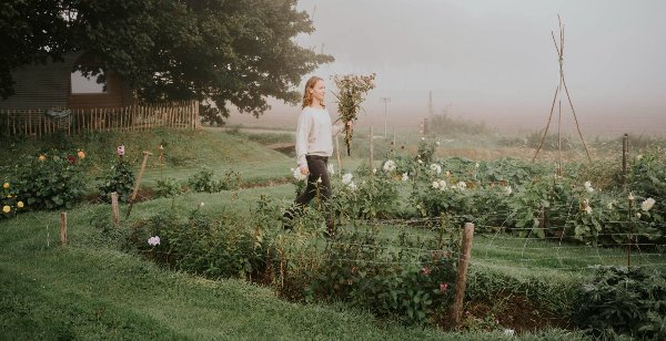 Een vrouw loopt door de pluktuin met een zelf geplukt boeket
