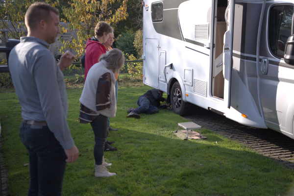 Er wordt onder toeziend oog van cursisten klein onderhoud gepleegd aan een camper