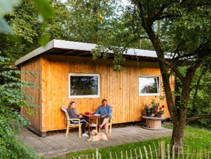 Twee mensen zitten op het terras van één van de nieuwe vakantiehuisjes op Camping Fiederels