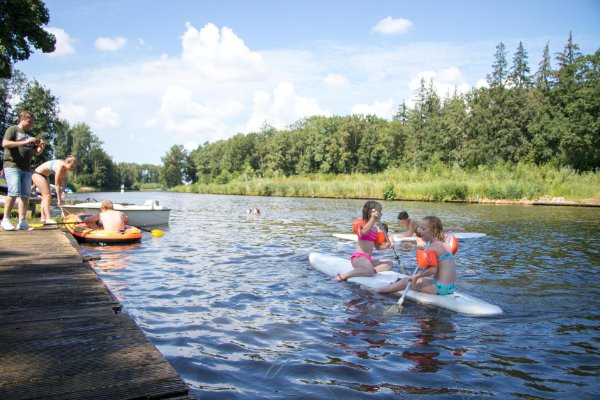 Kinderen spelen in bootjes en op surfplanken op de vaart bij Recreatiepark De Voorst