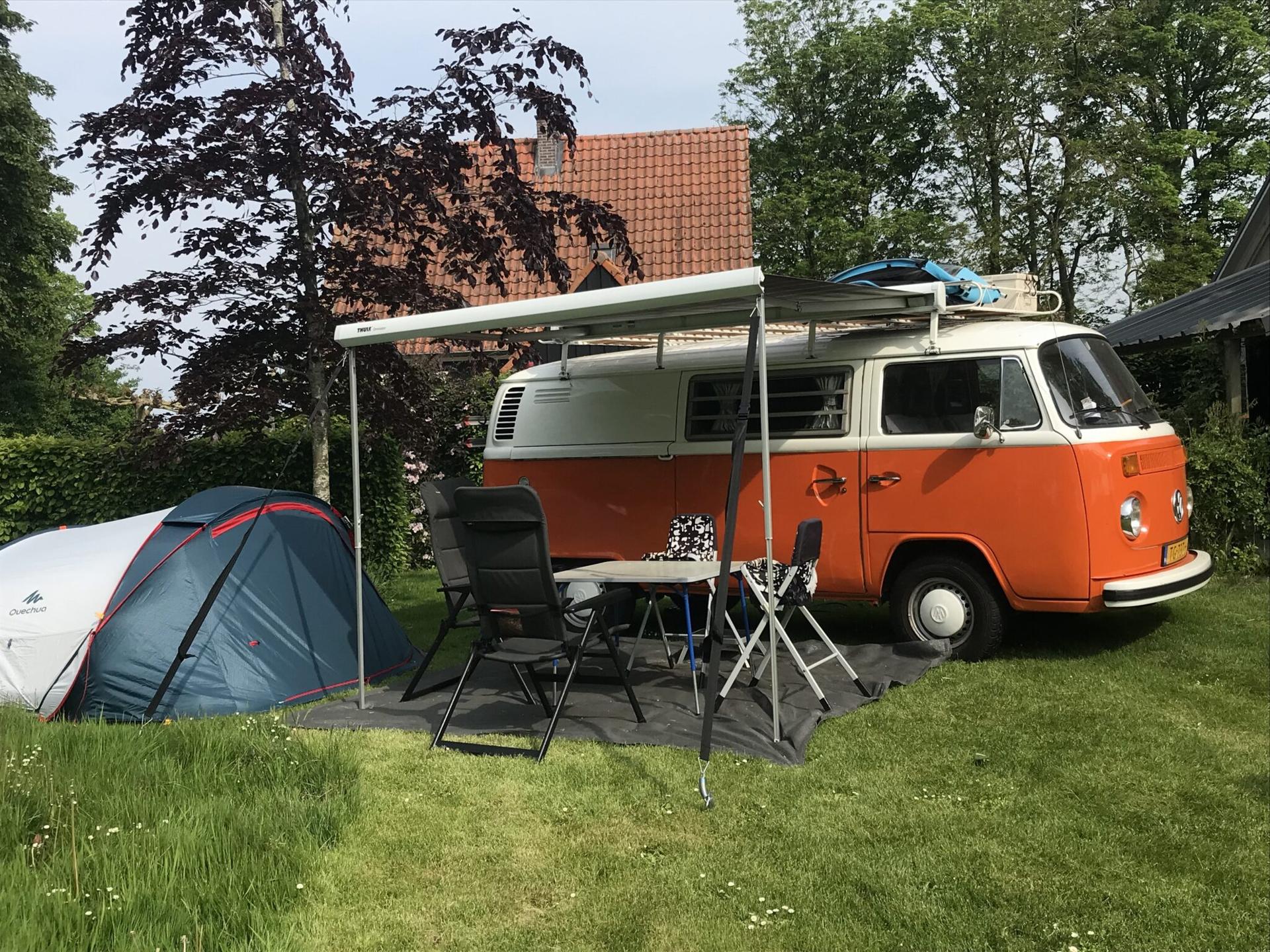Een VW-busje en een tent staan op de camping van De Zuiderkrib