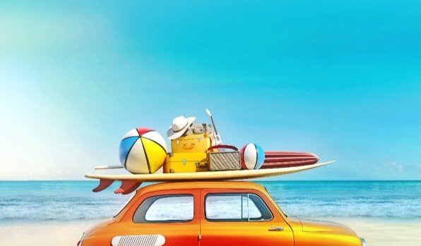 Auto op het strand, met surfplank en bagage op het dak