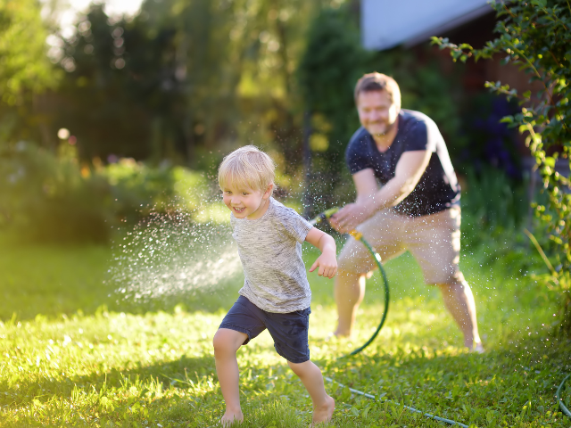 Vader spelend in tuin met zoon