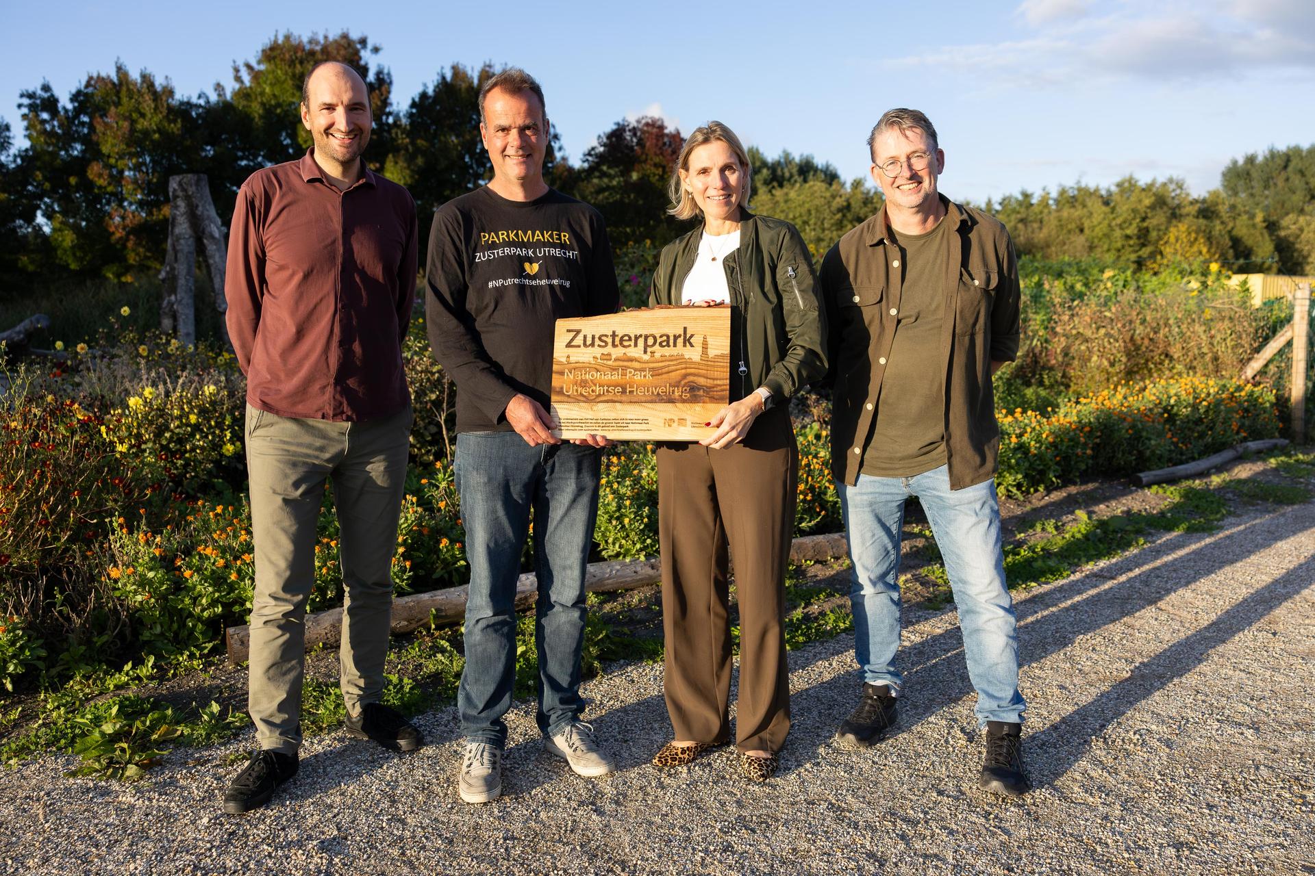 Ron Buiting, Taco Janonius en Cees van den Brink van Parkmakers Utrecht houden samen met Mirjam Sterk een bord van Zusterparken vast