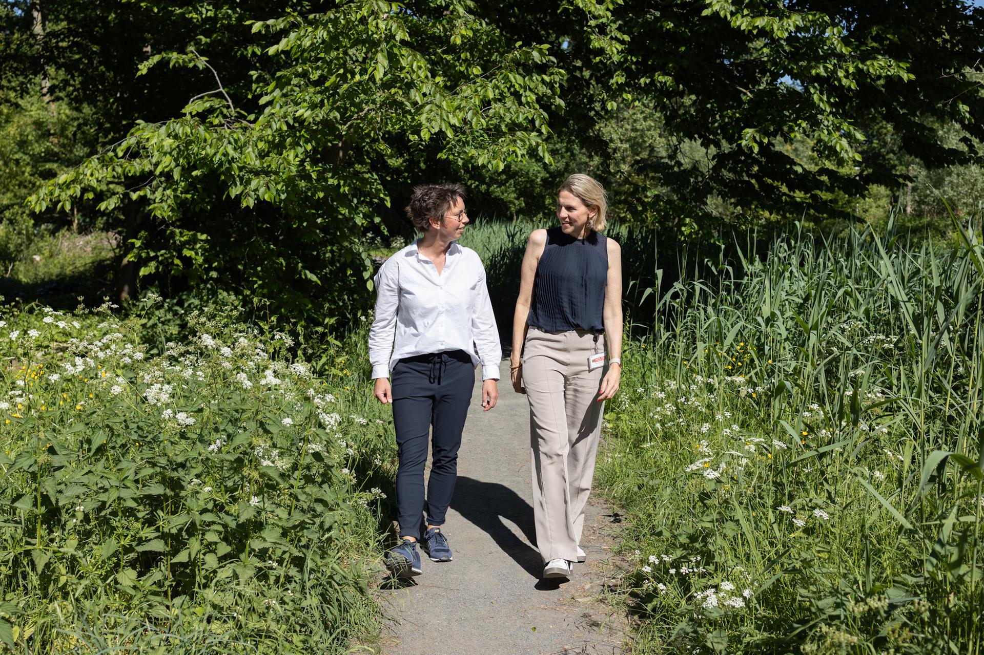 Ankie van Dijk en Mirjam Sterk wandelen in een groene omgeving.