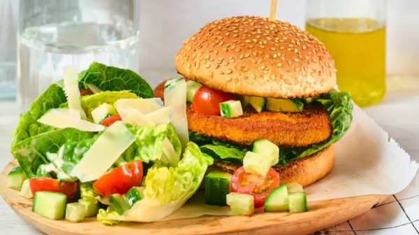 Een kipburger op een bord met sla