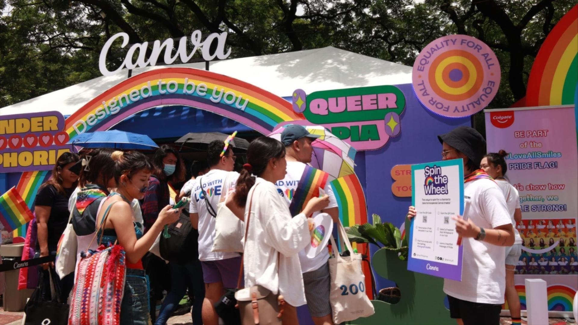  Canva Pride booth with rainbow over entrance and a group of people standing outside and inside of the booth