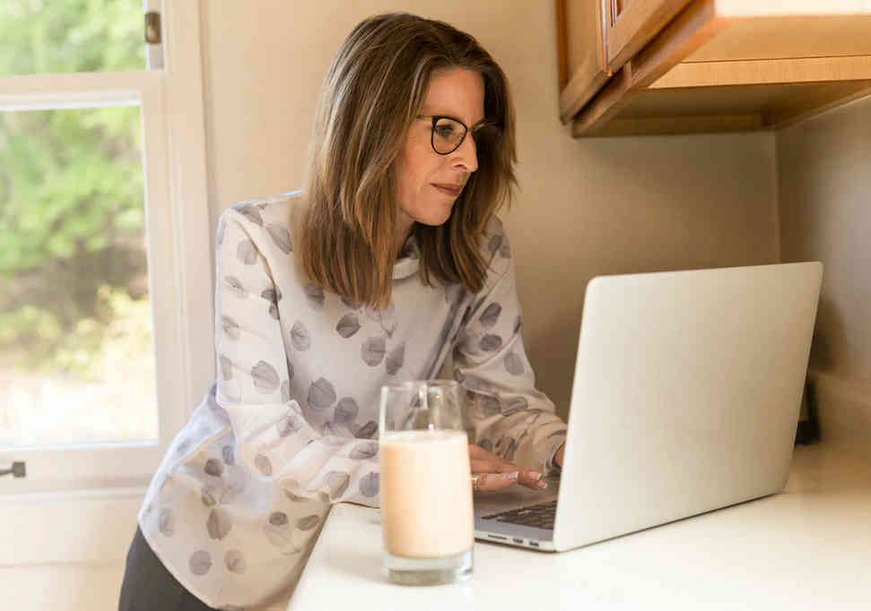 femme travaillant devant un ordinateur dans une cuisine