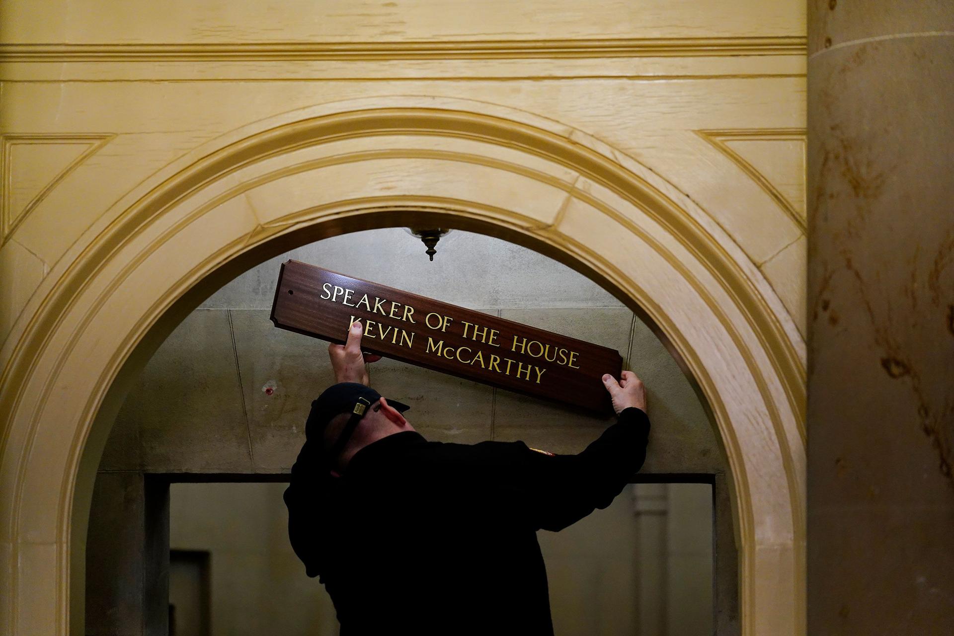 Someone removing the Speaker of the House name plate from a door
