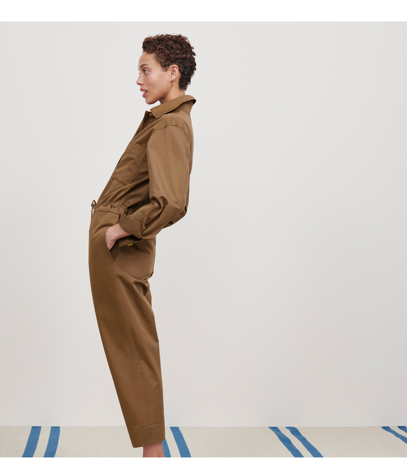 Image of a woman wearing a tan-colored jumpsuit.