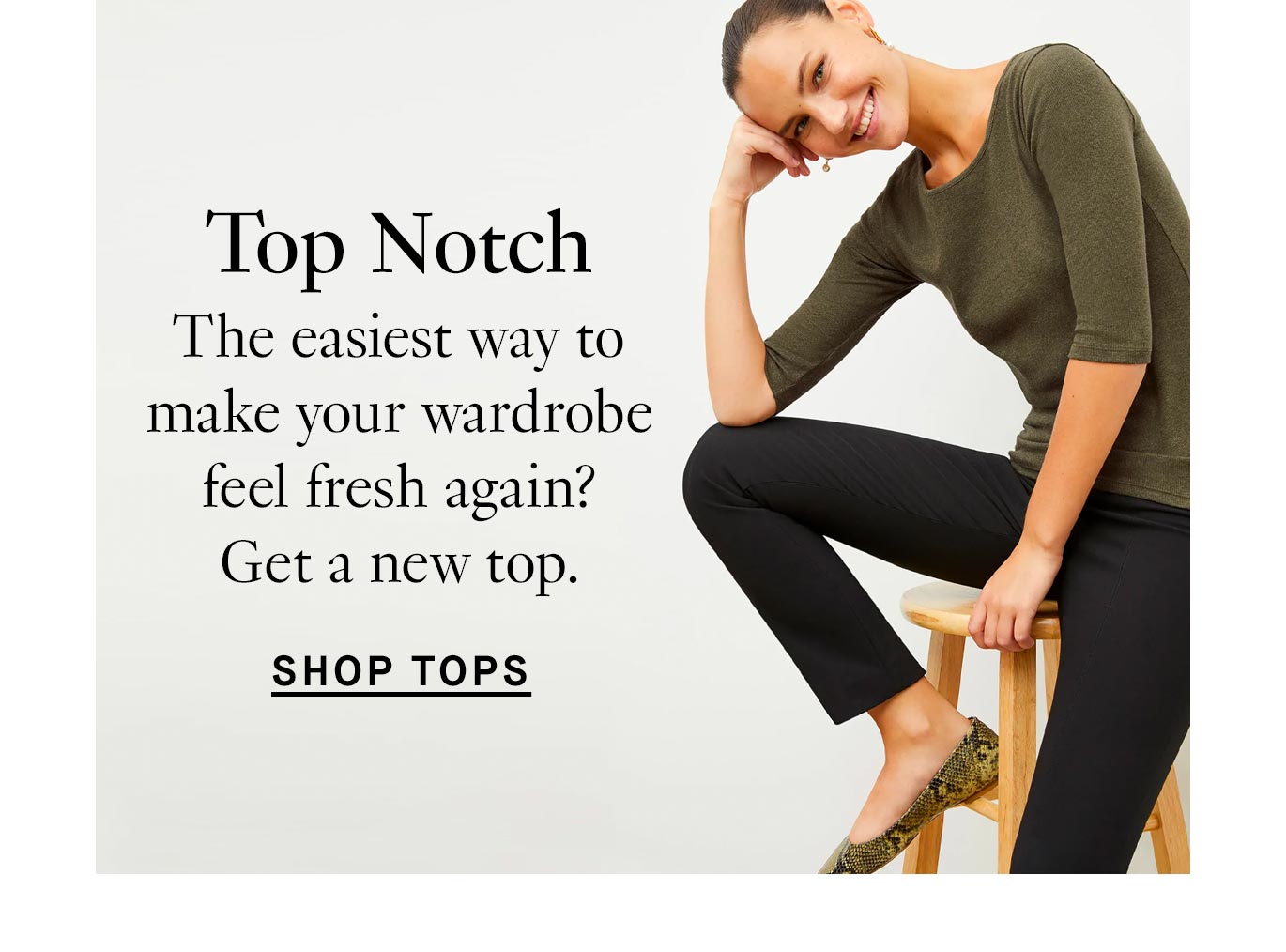 Image of a smiling woman with brown hair tied back into a bun and perched on a wooden stool. She's wearing black pants, snakeskin flats, and a mid-length sleeved green top. Black text overlay reads, ''Top Notch. The easiest way to make your wardrobe feel fresh again? Get a new top. Shop tops.''