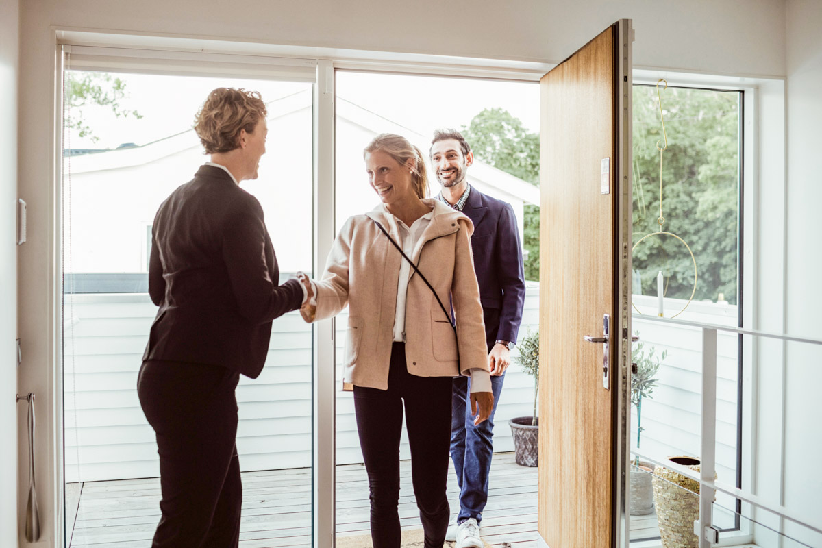 People walking into a real estate office and shaking hands with an agent