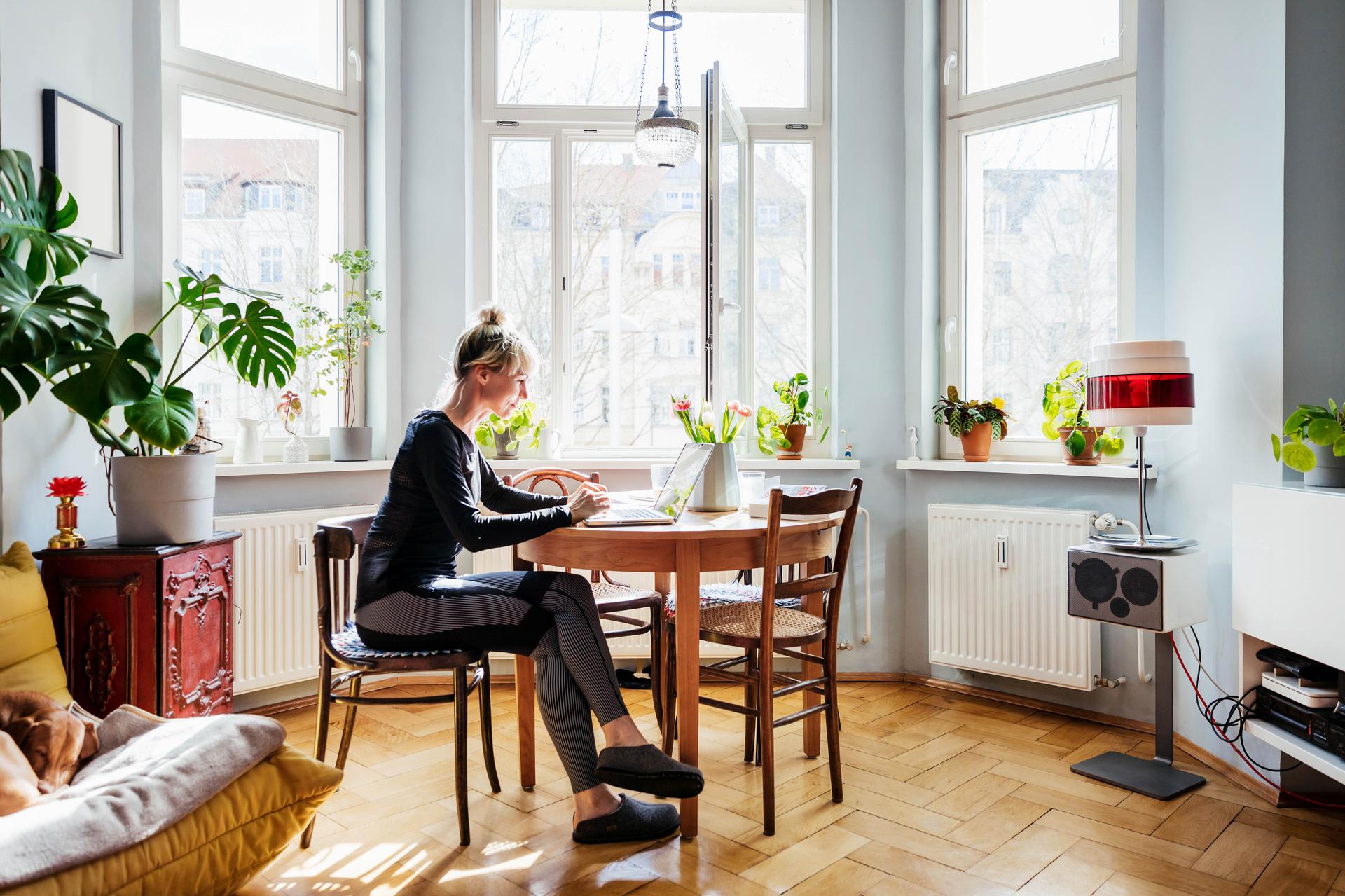 Women inside her house sitting at the kitchen table on her computer