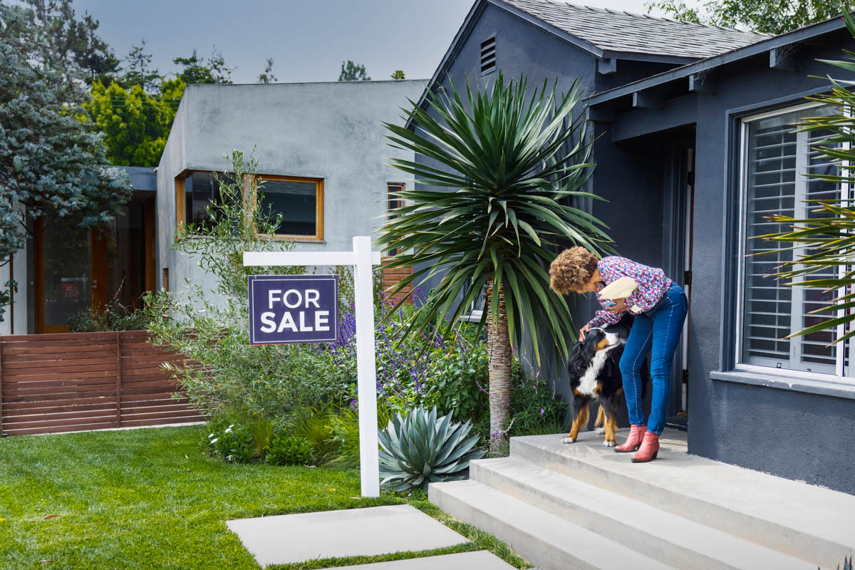 person in front of their house that's for sale with their dog