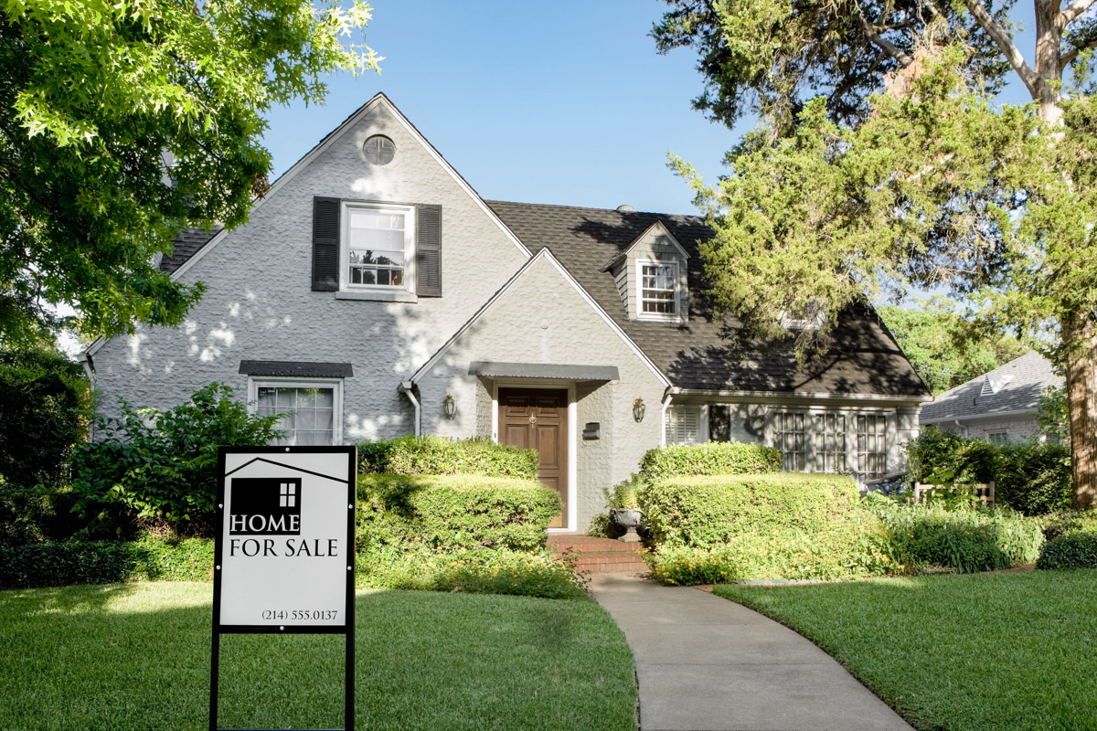 house with a home for sale sign in the front yard