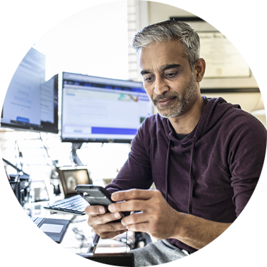 person in front of their computer on their cell phone