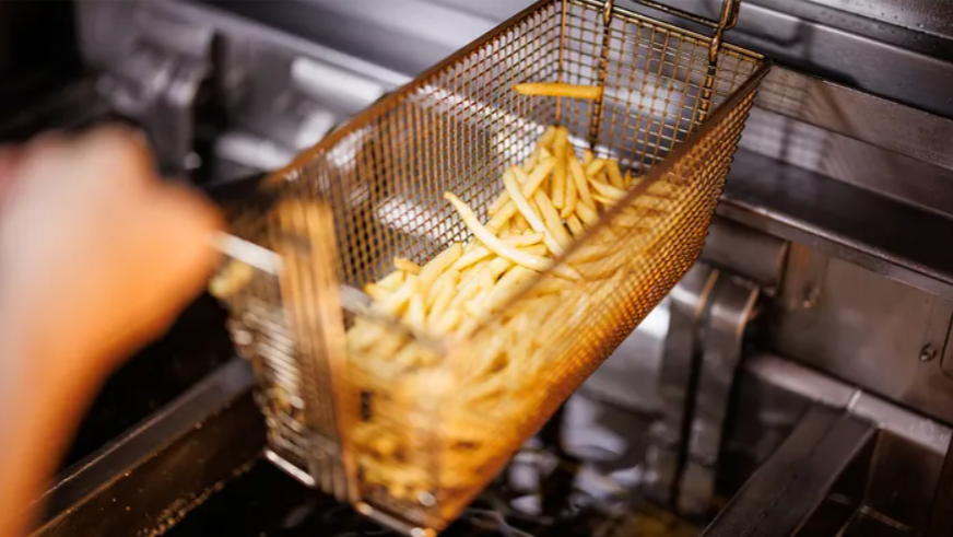 A basket of McDonald's french fries in a deep fryer