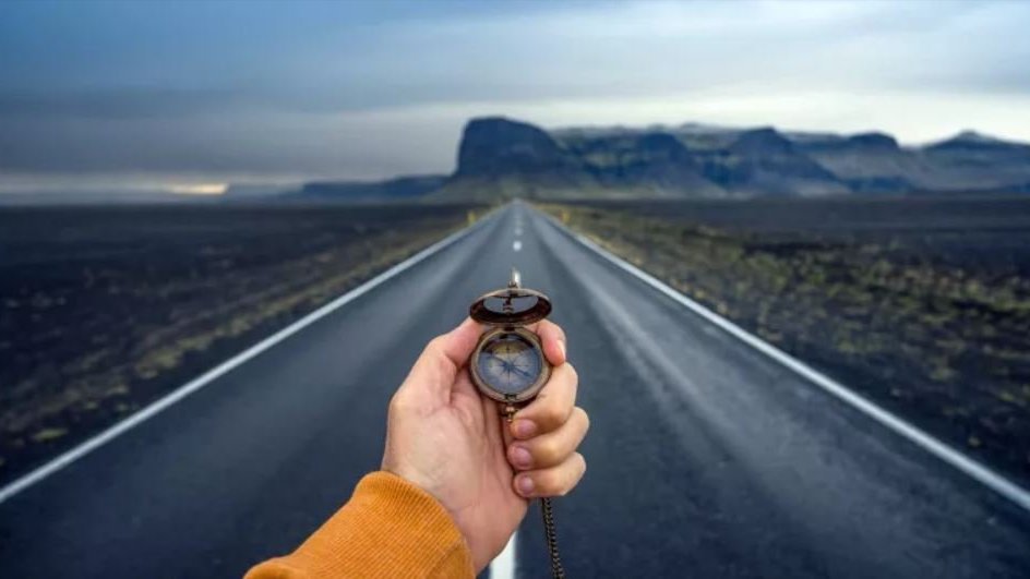 Person holding a compass on a road