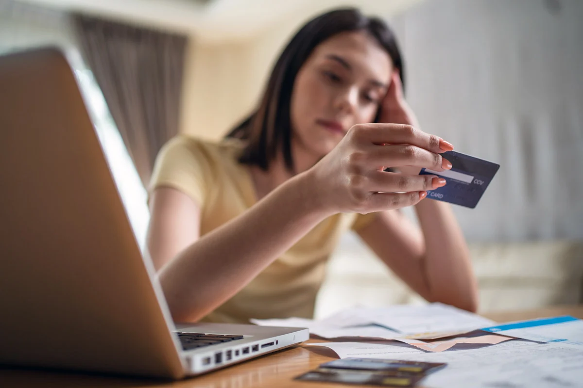 a woman looking at her credit card with regret