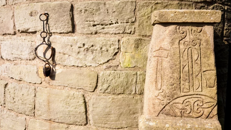The ancient Pictish symbol stone at the foot of the 11th century Irish Celtic round tower in Abernethy, Scotland.