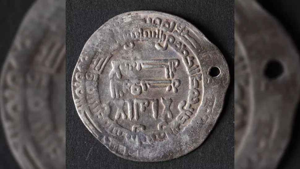 Silver coin showing several runes