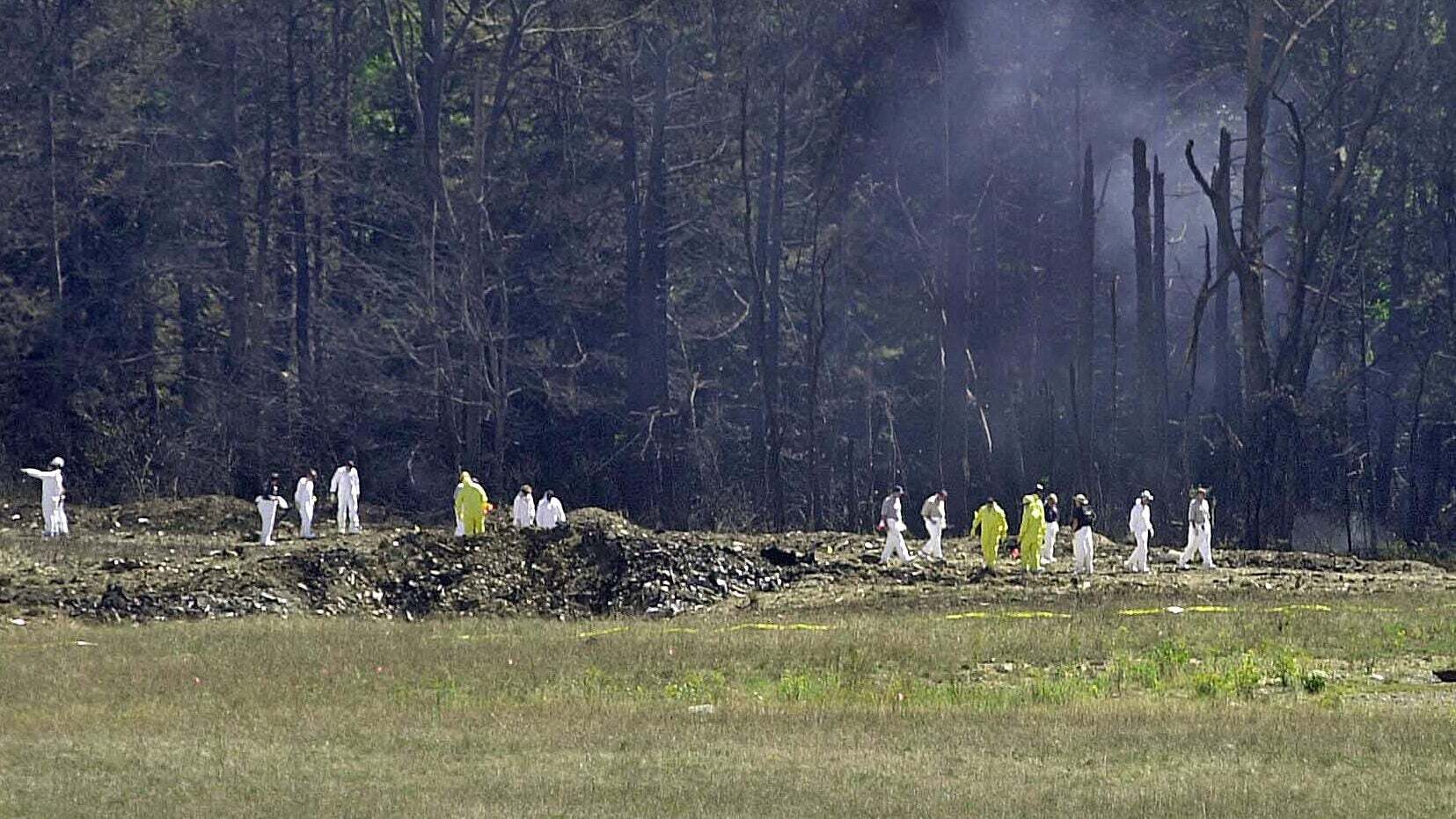 People in hazmat suits walking on a crash site