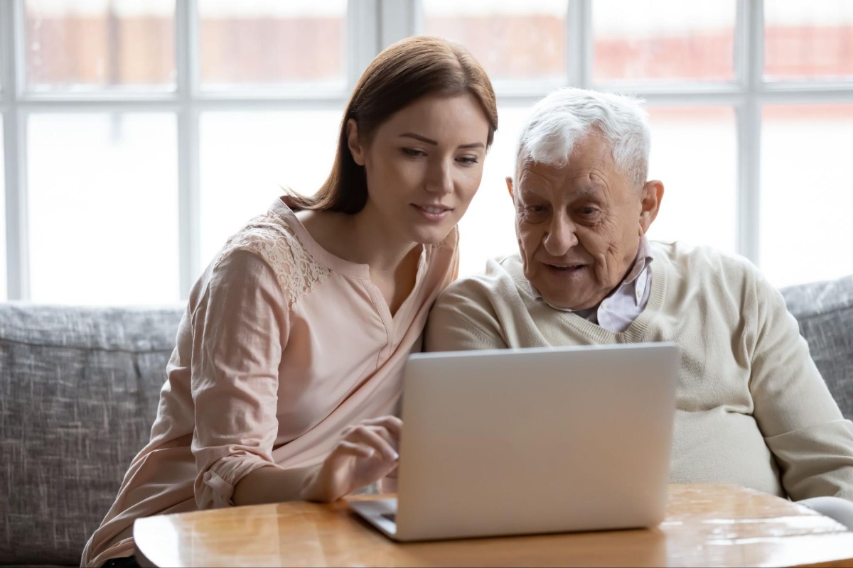 Younger woman looking at a laptop with an old man