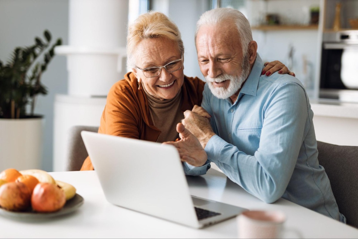 Old couple happily looking at a laptop